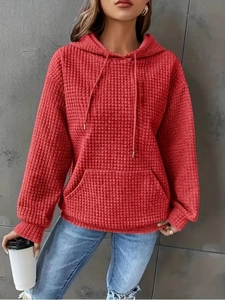 Detailed macro view of brick red waffle-knit fabric and drawstring on the hoodie