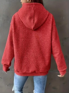 Rear view of a red hooded sweatshirt with textured waffle knit fabric and loose fit