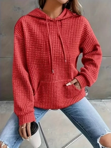 Detailed close-up of the textured waffle knit fabric and kangaroo pocket on a red hoodie