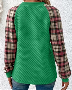 Dettaglio della trama trapuntata verde con maniche scozzesi rosse su una felpa casual