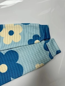 Dettaglio del tessuto waffle a fiori blu con polsino a coste che mostra la trama fine