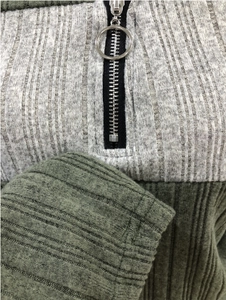 Détail du haut en maille gris et vert avec texture côtelée et fermeture éclair à anneau