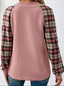 Dettaglio della trapuntatura a rombi rosa e maniche scozzesi retrò su una felpa casual