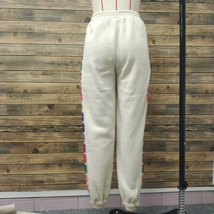 Back view of cream sweatpants featuring elastic waist and vibrant colorful side patterns