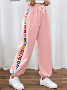 Detail of light pink joggers showing colorful floral side stripes and elastic drawstring waist