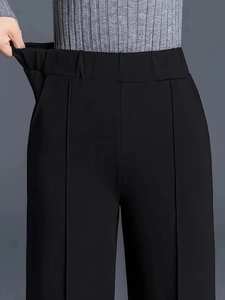 Detail of high-waist trousers showing elastic waistband stretch and drape texture