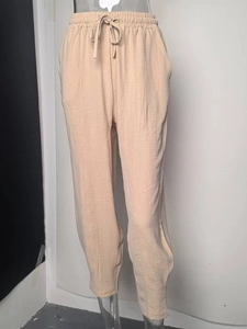 Detail of high waist drawstring waistband and waffle texture on beige vacation trousers