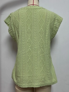Gros plan sur le t-shirt en maille vert clair avec jacquard en losange et texture ondulée