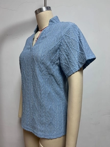 Macro detail of sky blue V-neck blouse showing intricate knit jacquard diamond textures