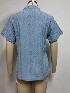 Macro detail of light blue short sleeve top with textured diamond knit pattern on back side