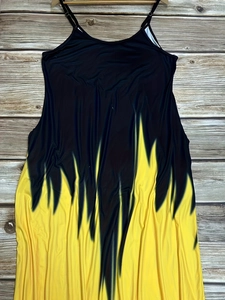 Robe longue à fines bretelles avec imprimé dégradé noir et jaune posée sur du bois