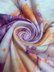 Close-up of vibrant purple and orange tie-dye fabric with soft knitted texture and drape