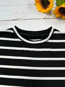 Classic black and white striped round neck T-shirt on a white rustic wooden background