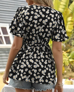 Detail of ruffled sleeves and white daisy floral print on black summer shirt