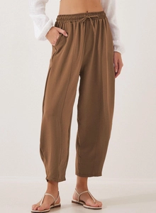 Detail view of brown wide-leg pants with elastic drawstring waist and side pockets