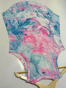 Detail of pink and blue marble print swimsuit on a wooden hanger with white background