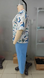 Detail of tropical print short sleeve top and light blue pants set on a mannequin