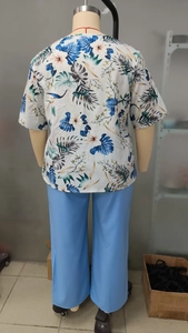 Detail of plus size short sleeve tropical floral print top and blue trousers set for summer