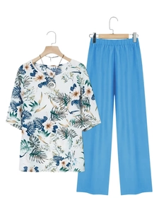 Detail of V-neck tropical leaf print short sleeve top with blue wide-leg trousers set