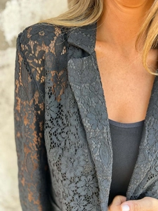 Detail of elegant black sheer floral lace fabric on women's blazer jacket