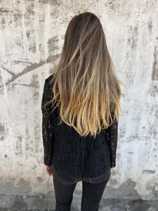 Detail of elegant black long-sleeve lace top with floral hollow-out pattern and semi-sheer texture