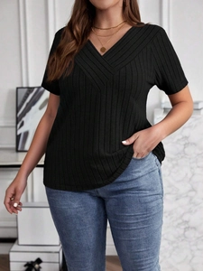 Detalle de camiseta negra con cuello en V, textura acanalada y diseño cruzado frontal