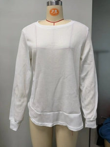 Detail of white waffle knit long sleeve sweatshirt showing fabric texture and round neck