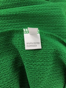 Detail of green wavy texture fabric with 95% polyester and 5% spandex material label