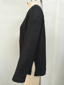 Dettaglio del tessuto a nido d'ape nero con spacco laterale e design con spalle scese