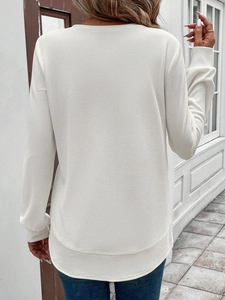 Detail of white waffle knit sweatshirt featuring a stylish hi-low curved hem design