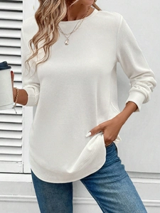 Detailed close-up of white waffle knit long sleeve top with crew neck and curved hemline