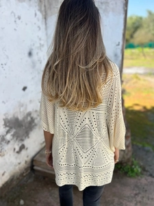 Macro view of cream crochet cardigan with geometric diamond hollow knit patterns