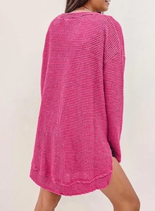 Dettaglio del tessuto a nido d'ape sulla maglia ampia rosso rosa con maniche lunghe e spacco