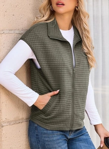Close-up of olive green quilted vest with standing collar and front zipper detail