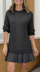 Detailed close-up of dark grey cable knit sweater dress with pleated chiffon hemline