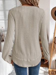 Detail view of the vertical ribbed texture and back fit of this beige knit sweater