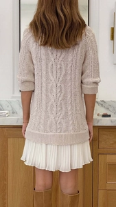 Rear view of knit mini dress showing cable stitch texture and pleated chiffon hemline