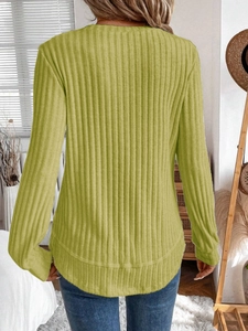Detail of ribbed knit texture and curved hem on a long sleeve crewneck sweater