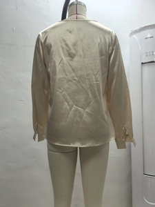 Vista trasera detallada de una camisa de satén champán con elegantes puños con abertura