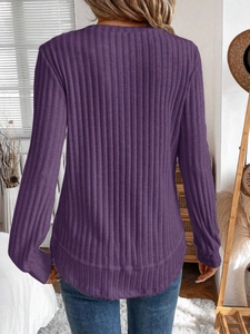 Macro shot of ribbed knit fabric texture and curved hem on a dark purple long sleeve top