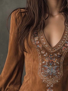Close-up of deep V-neckline with intricate bohemian floral embroidery on brown dress