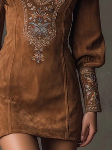 Close-up of bohemian brown faux suede mini dress with intricate floral embroidery details