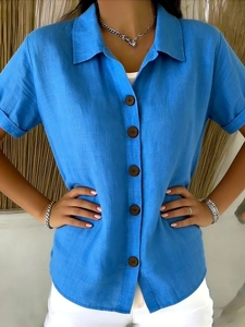Detail view of a bright blue cotton linen shirt with classic lapel and wooden buttons