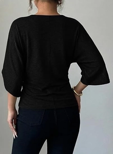 Detail view of black V-neck batwing sleeve top showing knitted texture and back cut