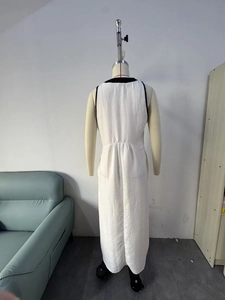 Détail d'une robe blanche sans manches montrant la texture plissée et le passepoil noir