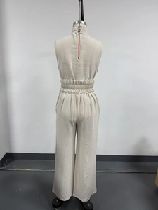 Detail of high waist elastic gathers and back button closure on beige sleeveless jumpsuit