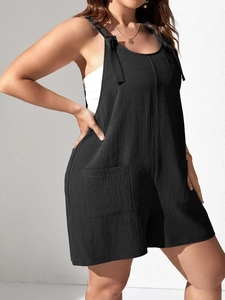 Detail of black textured romper featuring adjustable tie straps and front utility pockets