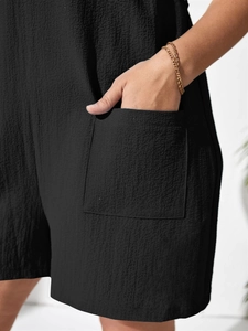 Detail of black seersucker jumpsuit featuring a large patch pocket and textured fabric
