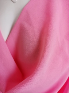 Detailed macro view of bright pink chiffon fabric with elegant crepon texture and soft draping