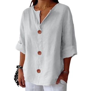 Detail of white cotton linen V-neck top with brown buttons and folded sleeve cuffs